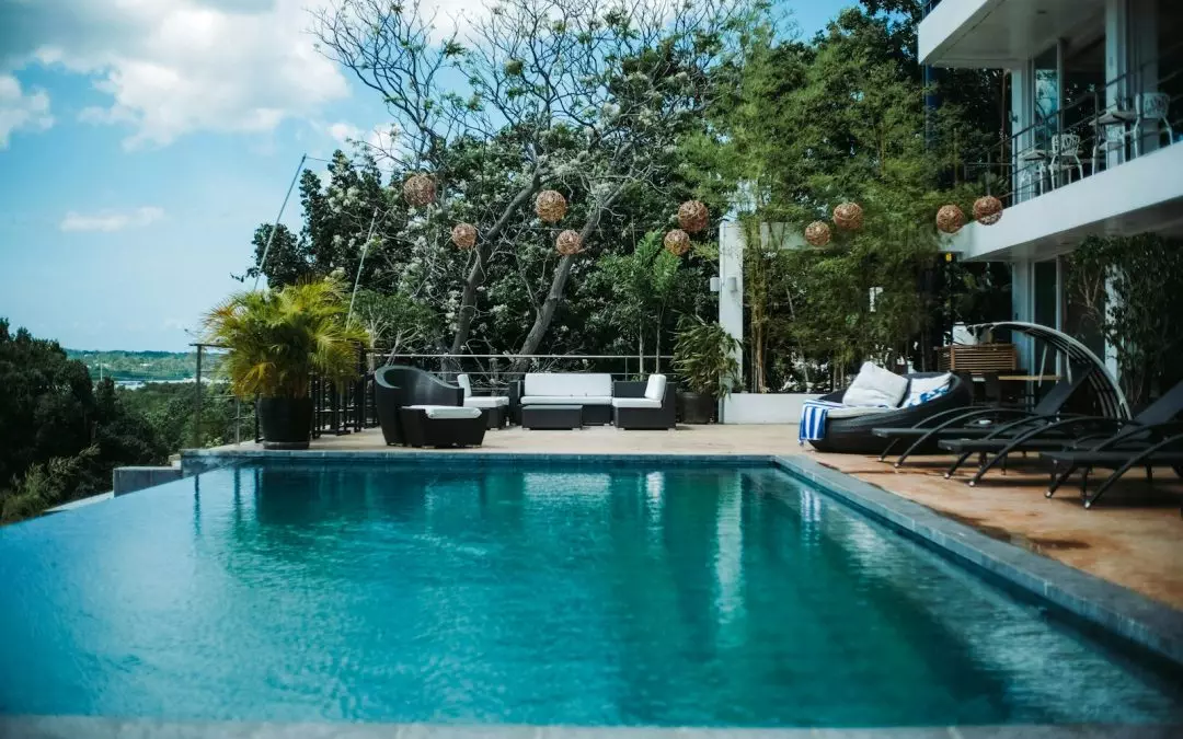 woman in black shirt sitting on white chair near swimming pool during daytime