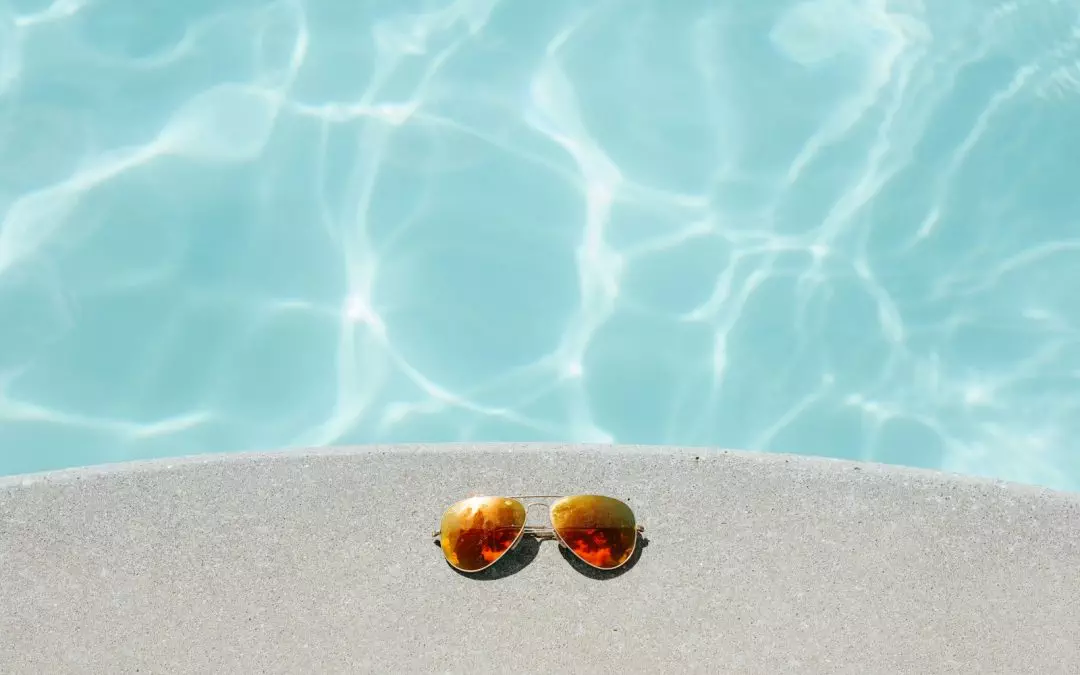 gold framed orange lens Aviator-style sunglasses beside pool