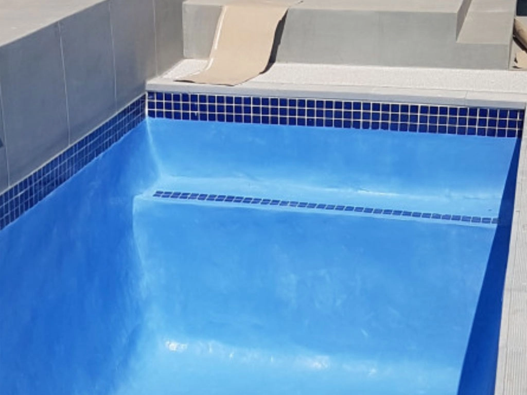 Empty finished small swimming pool of concrete, with blue interior, blue tiles.