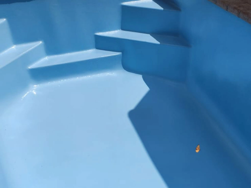 Cleaner concrete pool that is now renovated and blue.