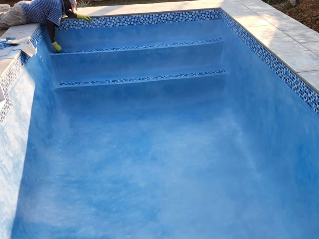 Small concrete pool project almost finished with blue interior.