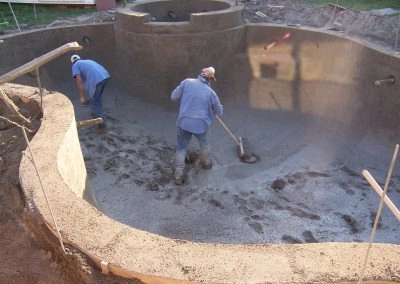 Concrete pool construction process, two guys sweeping the concrete floor of the swimming pool.